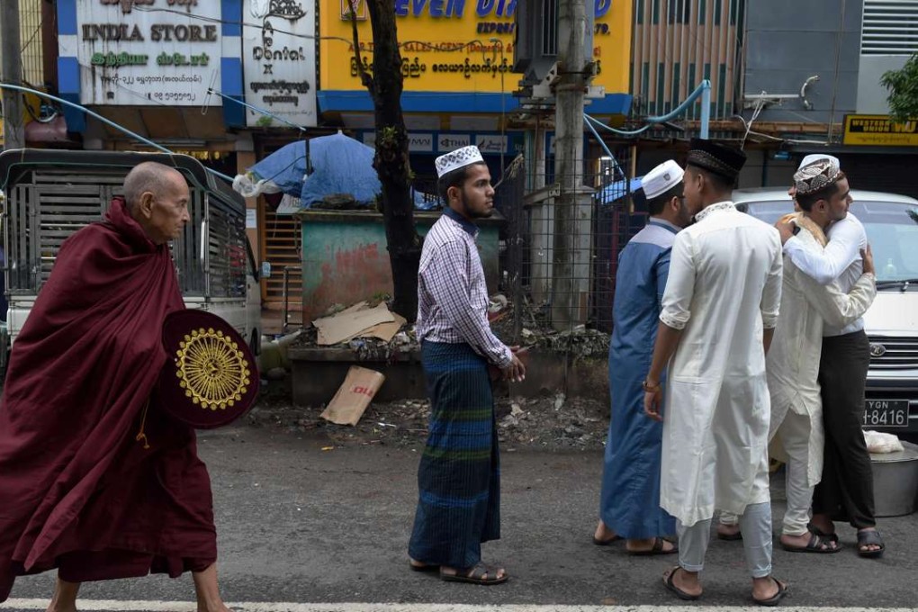 A Buddhist monk walks by Myanmar Muslims greeting one another outside the Narsapuri mosque in Yangon. Photo: AFP