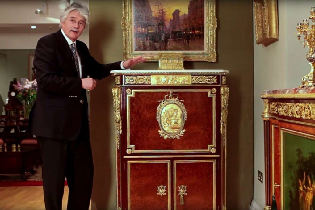 Furniture historian Christopher Payne poses next to a unique secretaire abattant, made as an exact copy of one in the Wallace Collection of art and antiques on display in London.