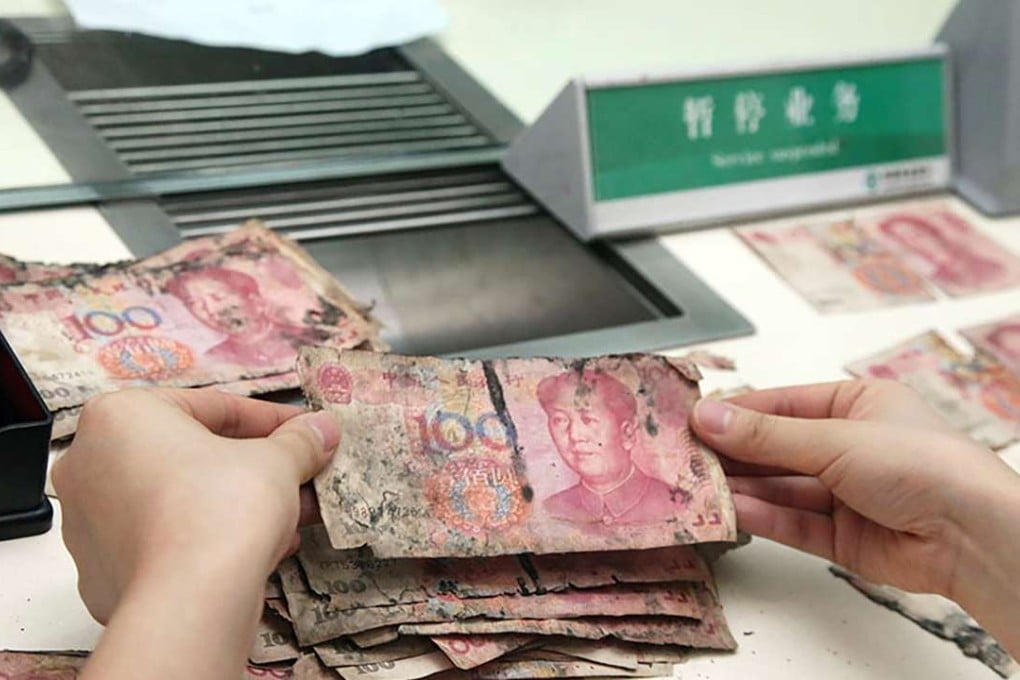 A bank teller inspects banknotes that had been stored in a humid room. Photo SCMP Pictures