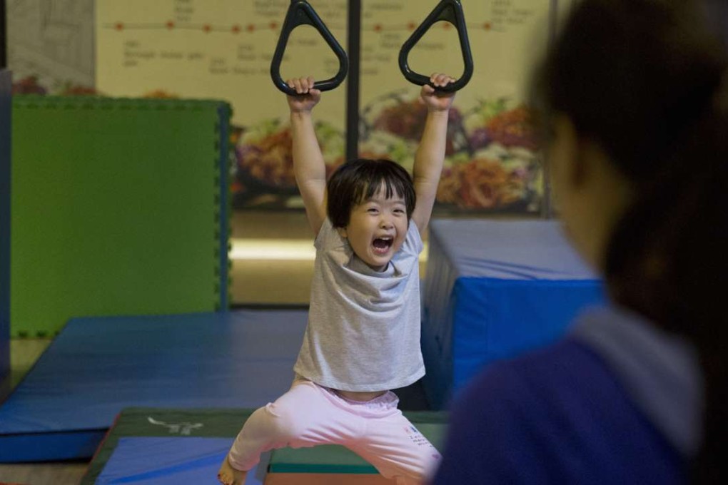 A child has fun swinging on rings during a class at the Inspire Sports private gym in Shanghai. Photo: AP