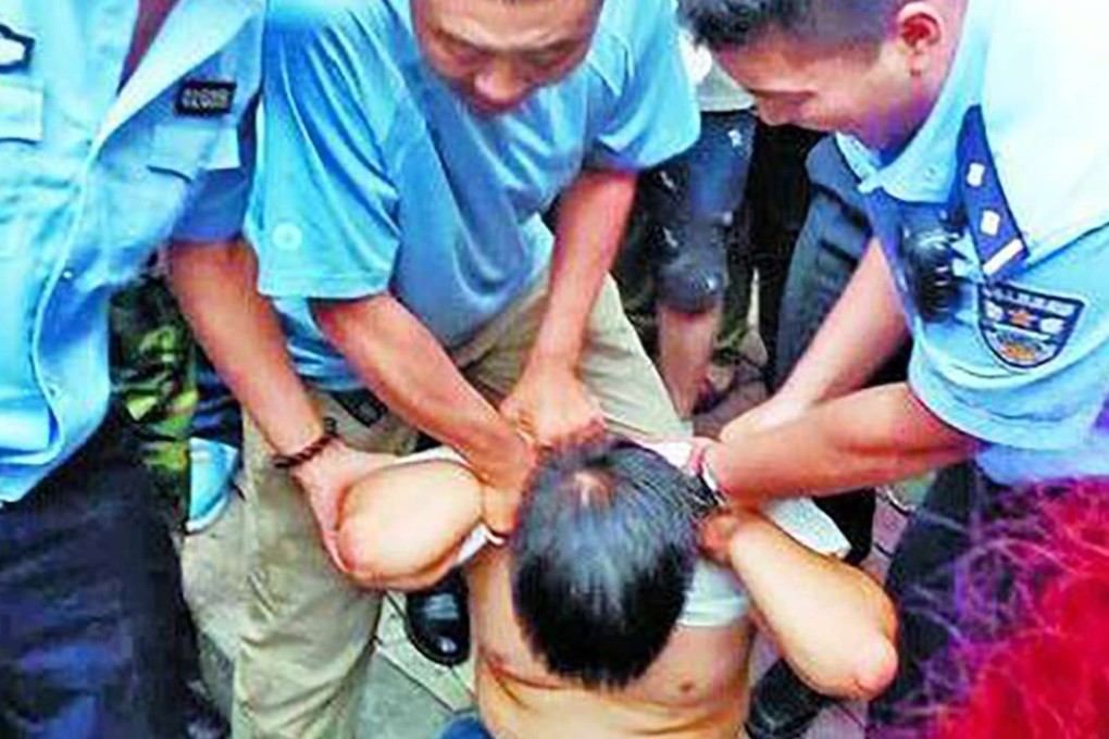 The Chinese robbery suspect is detained by police in Harbin after he was chased by residents after reportedly stealing 100,000 yuan from an elderly man. Photo: SCMP Pictures
