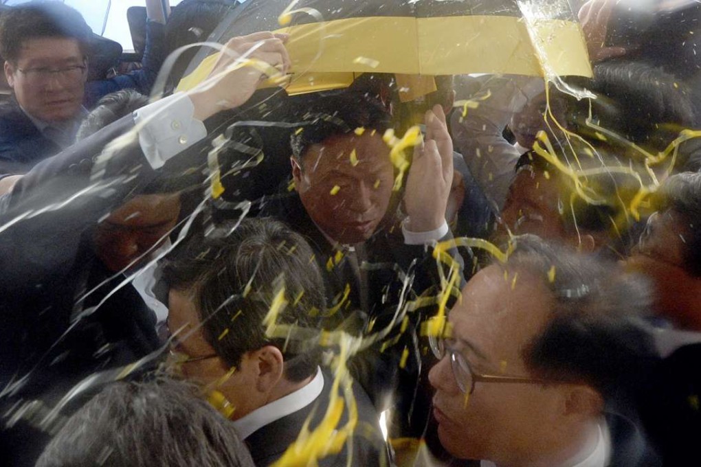 Bodyguards deploy umbrellas to shield South Korean Prime Minister Hwang Kyo-ahn (bottom centre) from incoming eggs thrown by angry locals in Seongju. Photo: AP