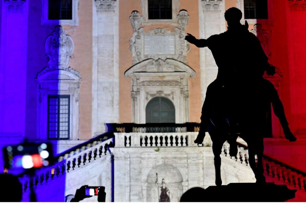 People take pictures as the colours of the French flag are projected on the Campidoglio in central Rome on July 15. Photo: AFP