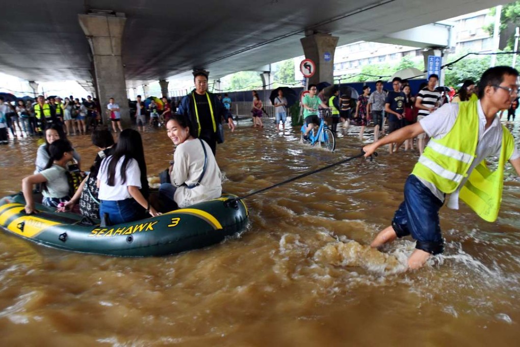 A rescuer helps people with an inflatable boat in flood water in Wuhan, Hubei province. Photo: AFP