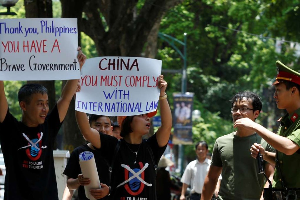 A policeman tries to stop anti-China protesters holding placards during a demonstration in front of the Philippines embassy in Hanoi. Photo: Reuters