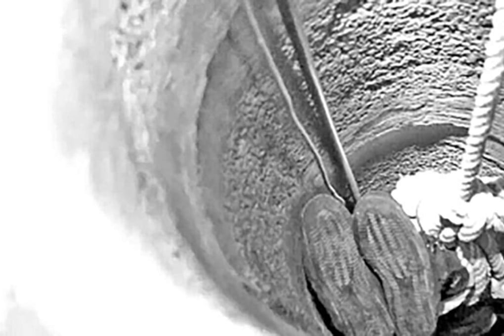 A policeman is lowered headfirst into a well to rescue an old man. SCMP Pictures