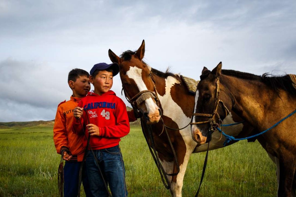 Young jockeys stand by their horses before the race starts. Photos: Tessa Chan