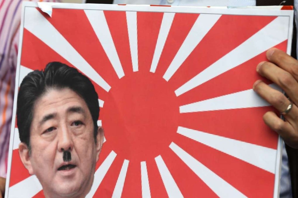 A protester holds a picture of Shinzō Abe outside Japanese Consulate General in Admiralty to mark the 79th anniversary of Japanese invasion in China. Photo: Dickson Lee