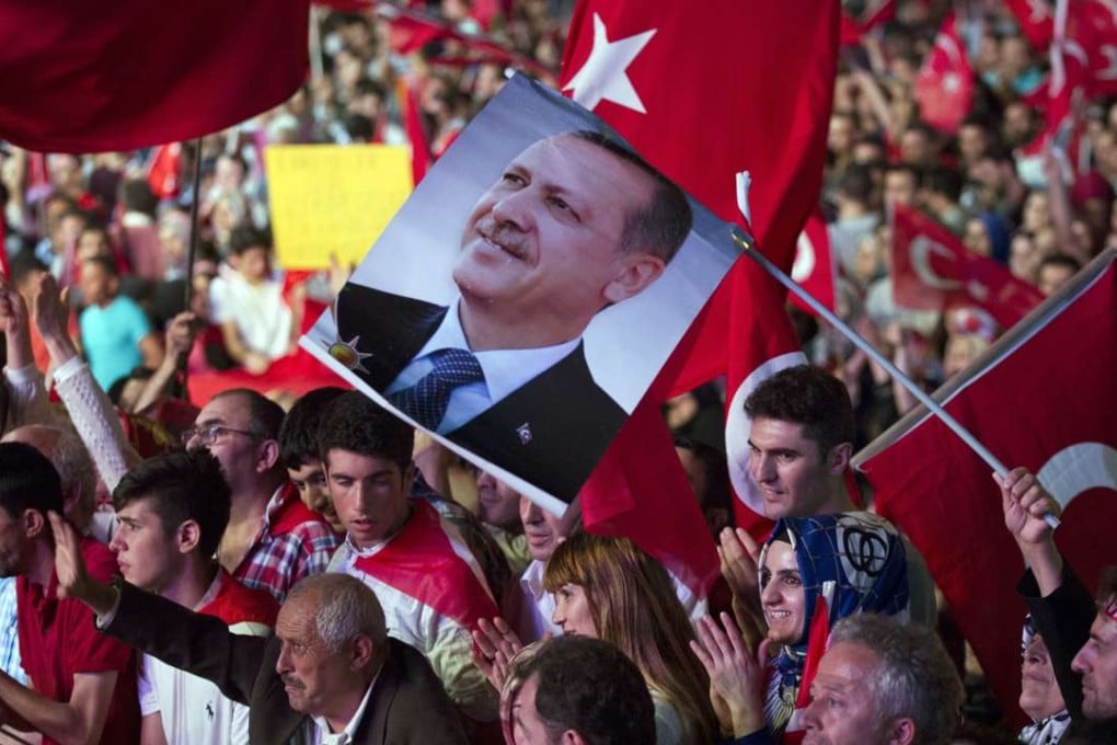 Government supporters wave Turkish flags and hold a picture of Turkish President Recep Tayyip Erdogan during a rally in Taksim Square, Istanbul, on Tuesday. Photo: AP