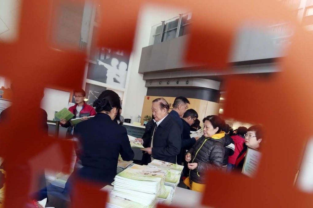 HOS applicants take forms and guides on the overview of the main sales arrangements and sales booklets of subsidised housing developments. Photo: K. Y. Cheng