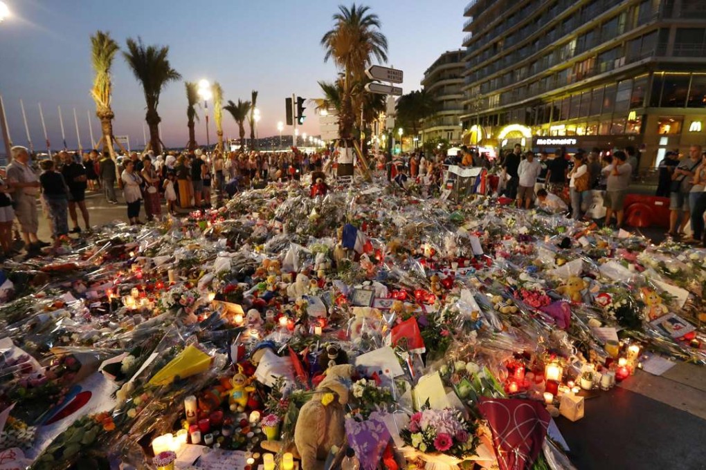 People stand in front of flowers, candles and messages laid at a makeshift memorial in Nice on Monday, in tribute to the victims of the deadly attack on the Promenade des Anglais seafront which killed 84 people. Photo: AFP