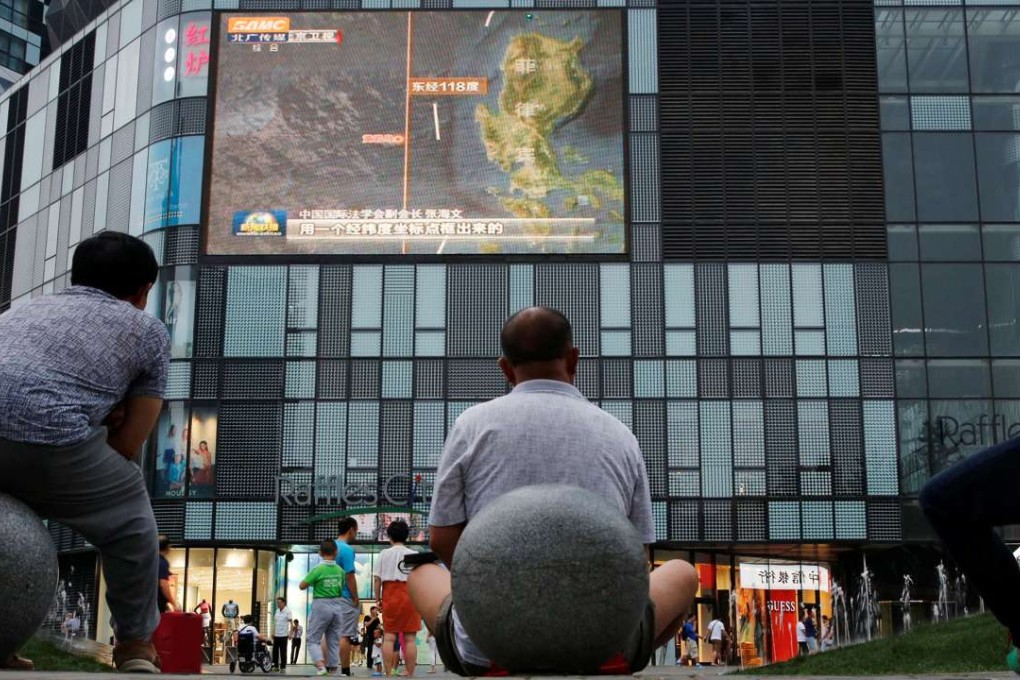 People outside a shopping mall in Beijing watch a TV news broadcast about the South China Sea. Photo: Reuters