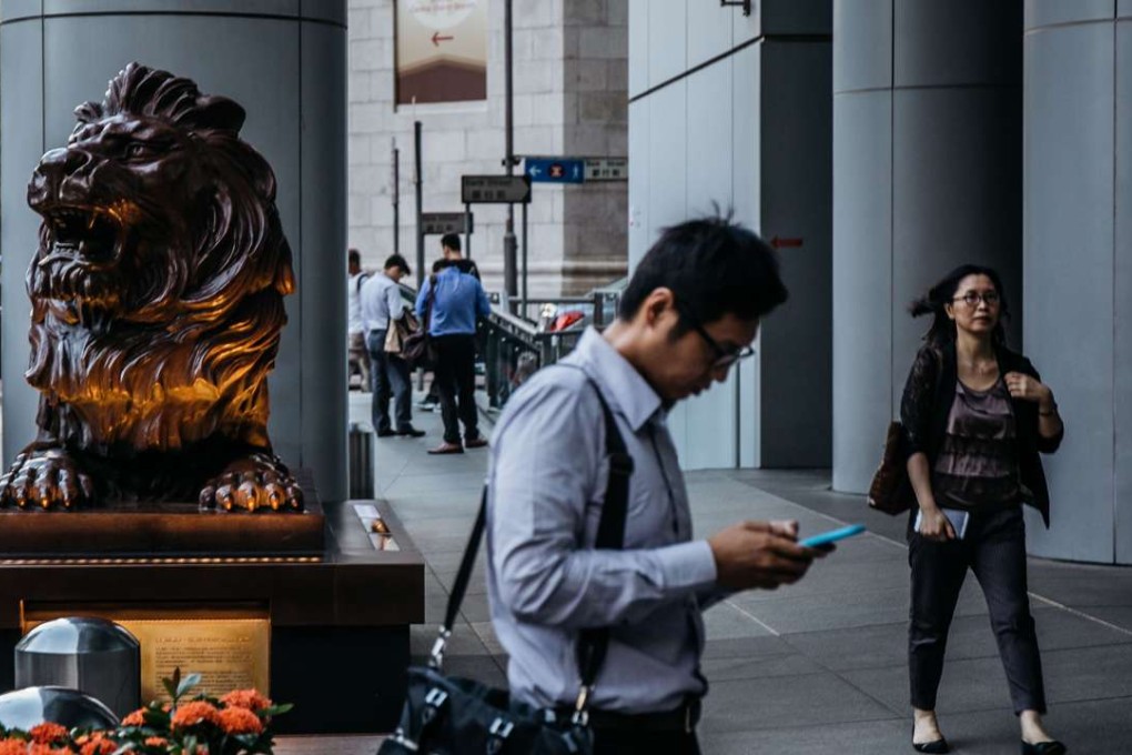 A man uses his mobile near the famous lion statues below the main HSBC building in Central. After dropping on Tuesday, the Hang Seng index increased 0.97 per cent on Wednesday to end at 21,882.48. Photo: Bloomberg