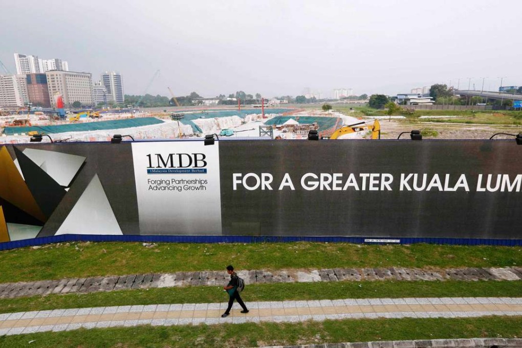 A man walks past a 1MDB billboard at the funds flagship Tun Razak Exchange development in Kuala Lumpur, last year. Photo: Reuters