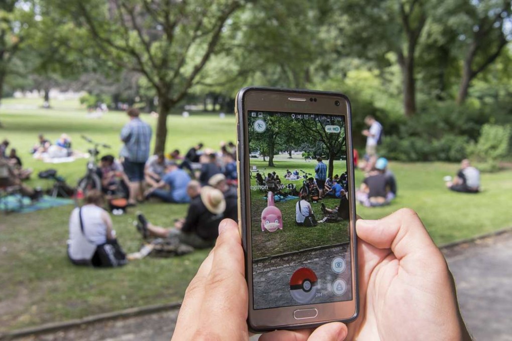 A player uses the Pokemon Go app, with other users pictured in the background. Photo: Alamy