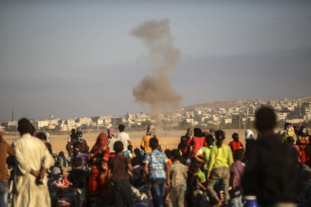 Syrian Kurds look at smoke billowing after a mortar attack near the Syrian border at the southeastern town of Suruc in Sanliurfa province, on September 20, 2014. Picture: AFP