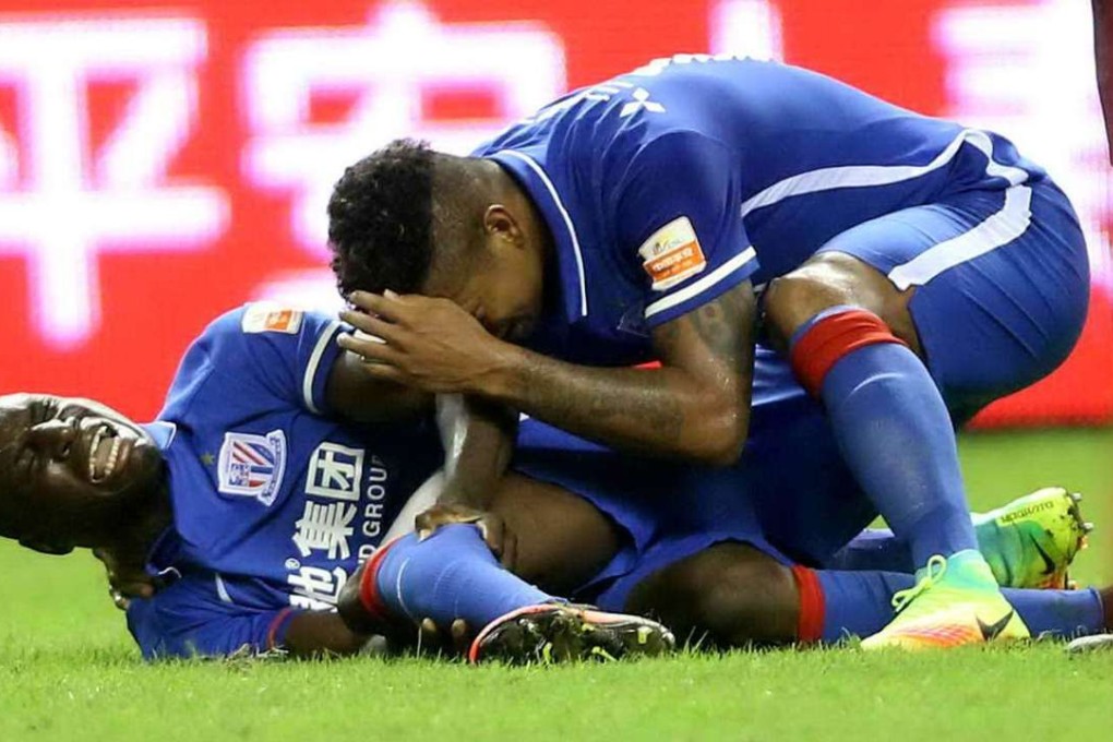 (FILES) This file photo taken on July 17, 2016 shows Demba Ba (L) of Shanghai Shenhua reacting after breaking his left leg during the 17th round football match of the Chinese Super League against Shanghai SIPG in Shanghai. Demba Ba's surgeon arrived late on July 21, 2016 in Shanghai and declared he was confident the former Chelsea striker would return to competitive football. / AFP PHOTO / STR
