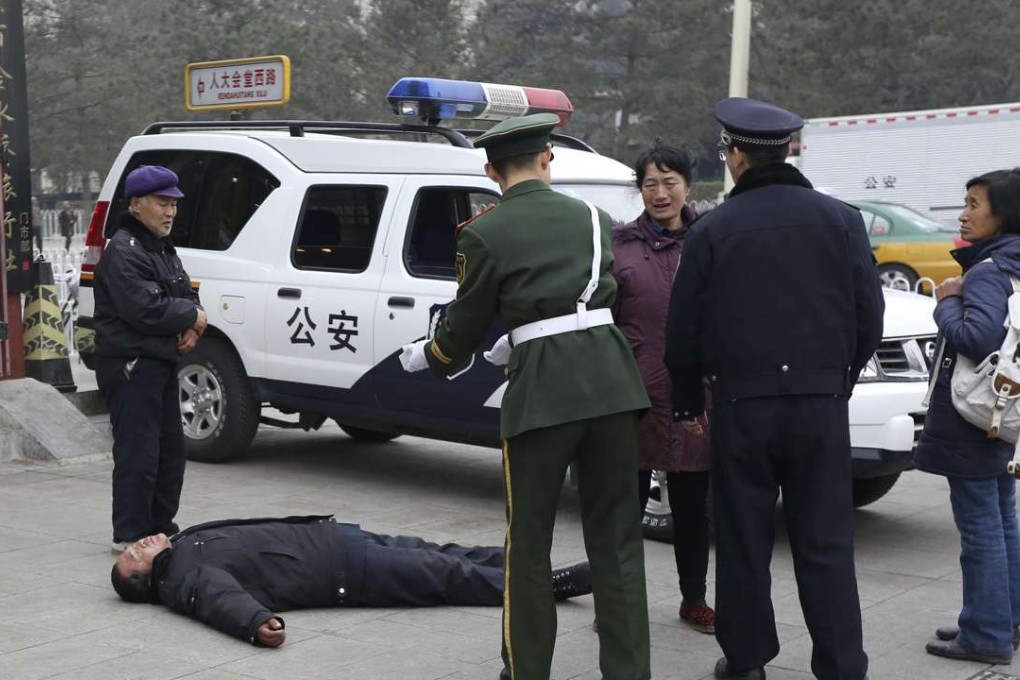 Authorities ask a petitioner to stand up as he lies on the ground after being stopped from petitioning outside the Great Hall of the People in a file photo from 2013. Photo: Reuters
