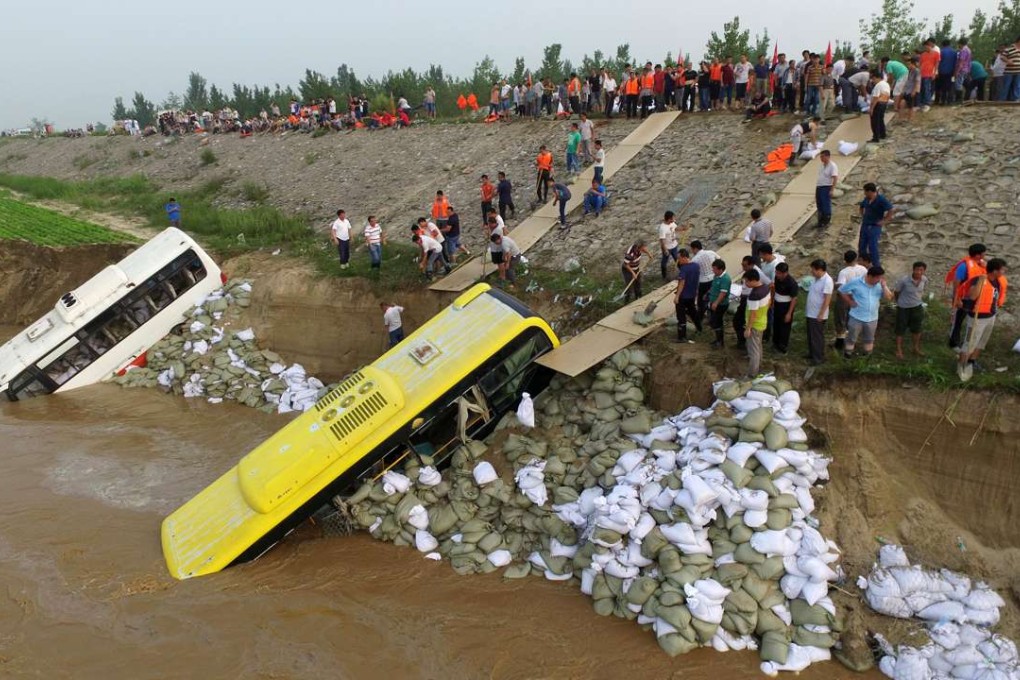Armed Police and villagers in Xingtai, Hebei province, push disused buses and sandbags on to a levee to prevent it collapsing after days of torrential rain. Photo: China News Service