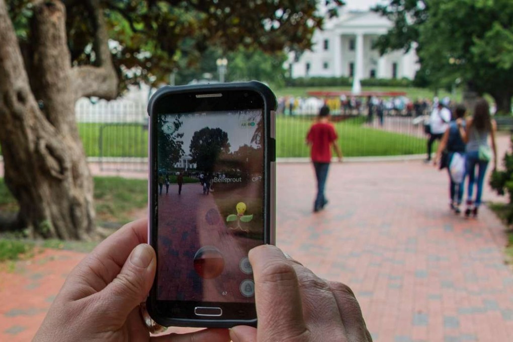A woman holds up her cell phone as she plays the Pokemon Go game in Lafayette Park in front of the White House in Washington on July 12. Pokemon Go fever has been sweeping western markets, but Chinese customers might have to wait some time to play along. Photo: AFP