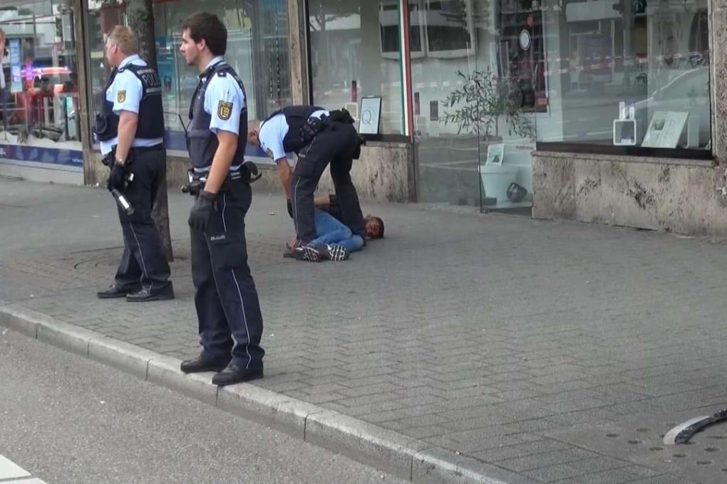 In this photo taken from video, police arrest a man suspected of hacking a woman to death with a machete in Reutilingen, Germany, on Sunday. The alleged murder weapon can be seen front right. Photo: AP
