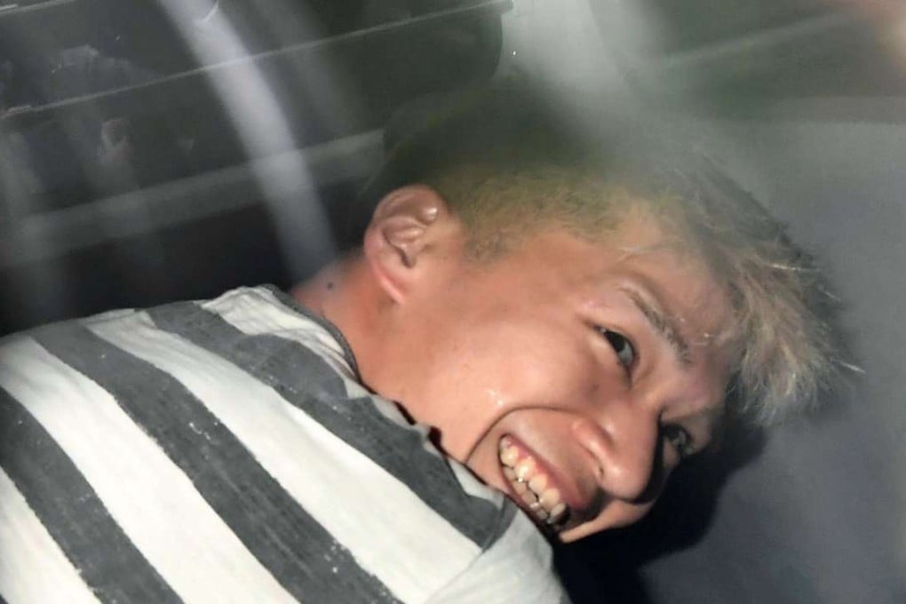 Satoshi Uematsu, who admitted stabbing dozens of residents at a facility for the disabled, grins for photographers as he is taken away in a police vehicle. Photo: Kyodo
