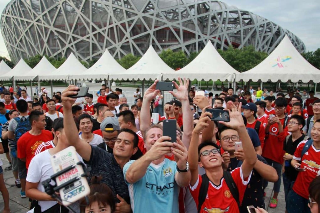 Fans take selfies as they gather near the Bird's Nest stadium, after the match between Manchester United and Manchester City was called off. Photo: Reuters
