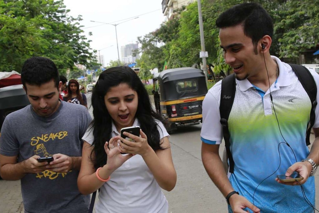 Young Indians look at their screens as they walk along playing Pokemon Go in Mumbai. Photo: AP