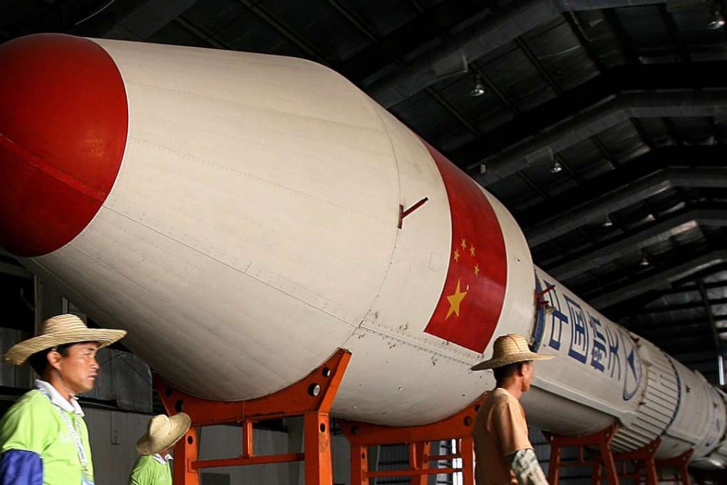 Chinese workers walk past a Long March Rocket. Photo: AFP