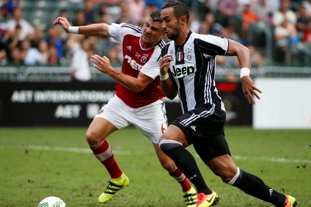 Medhi Benatia chases after the ball with South China's Russell Andrew James. Photos: Reuters