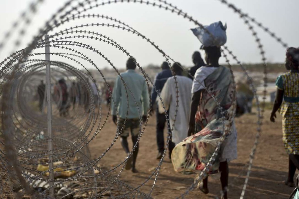 Displaced people walk next to a razor wire fence at the United Nations base in Juba, South Sudan. Photo: AP