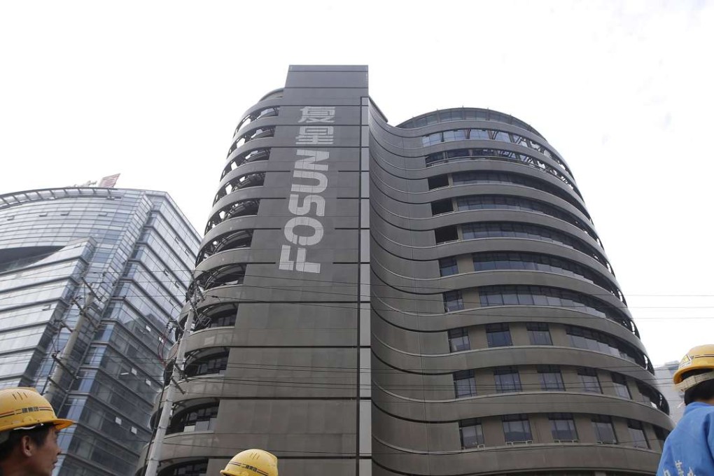 Construction workers walk past a building of the headquarters of Fosun International, in Shanghai, China. Photo: Reuters
