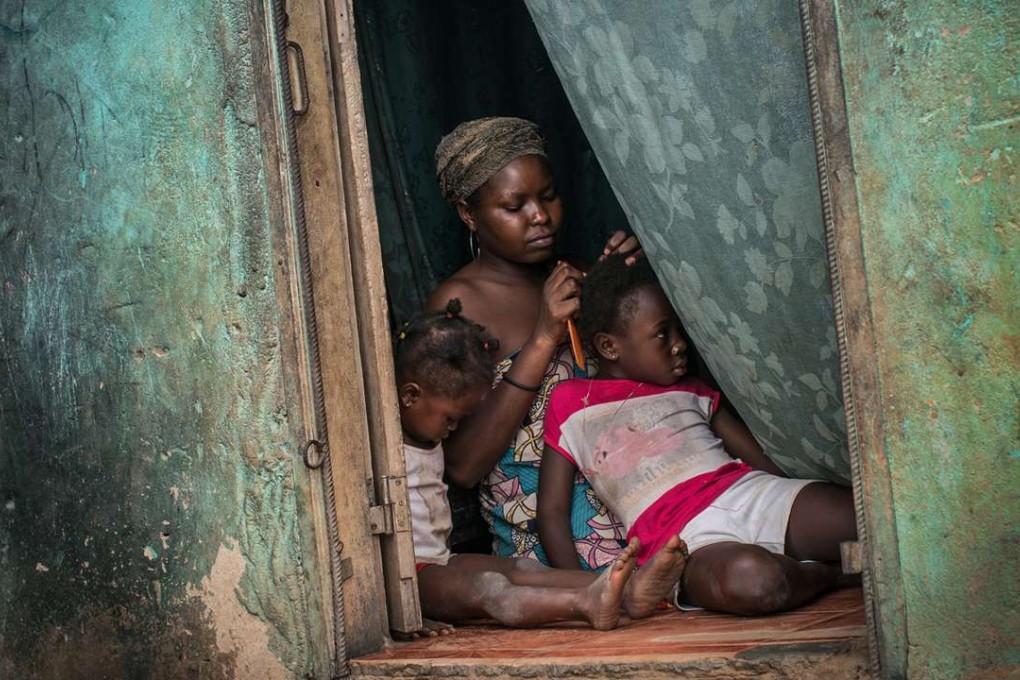 A mother braids her daughter's hair in a poor neighbourhood overlooking Cabinda, a heavily guarded territory that accounts for half the oil output from Africa's top petroleum producer. Photo: The Washington Post