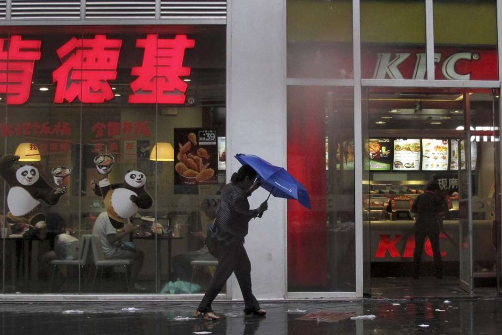 A woman holds an umbrella as she walks past a KFC restaurant in Beijing, China as shifting tastes prompt its owner Yum Brands to consider selling its business there. Photo: AP