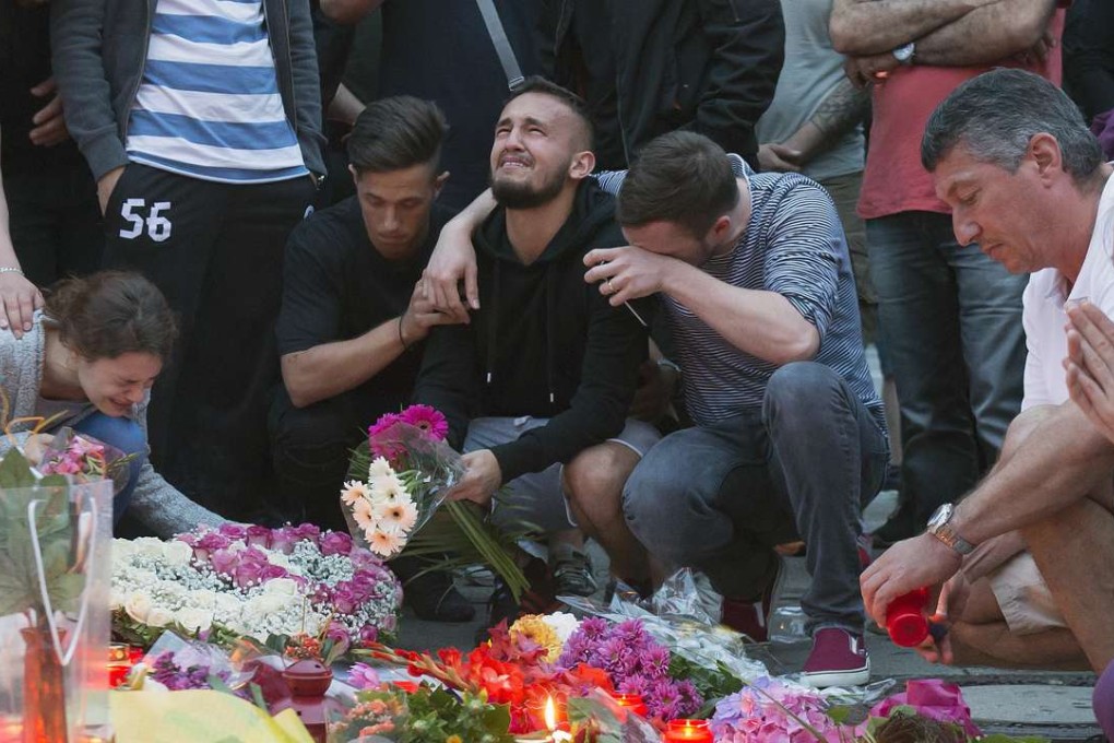 Tears flow as floral tributes are placed near the Olympia shopping centre in Munich where a lone gunman killed nine, including children, on July 22. Photo: AP