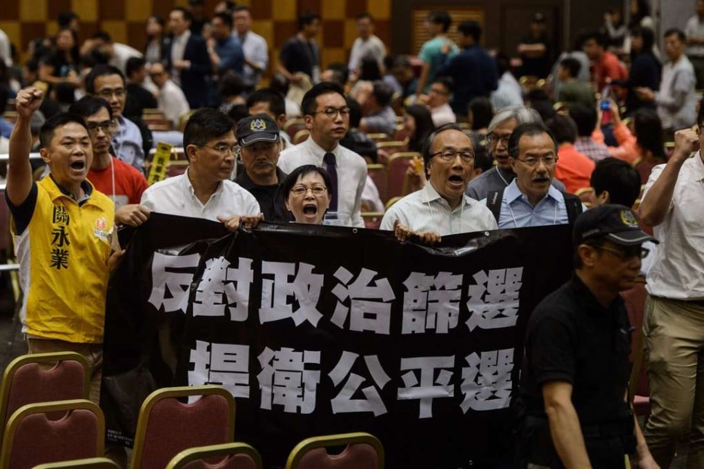 Pan-democrats shout slogans and hold a banner which translates as “Oppose Political Vetting, Defend Fair Elections” during a Legislative Council election briefing for candidates last week. Photo: AFP