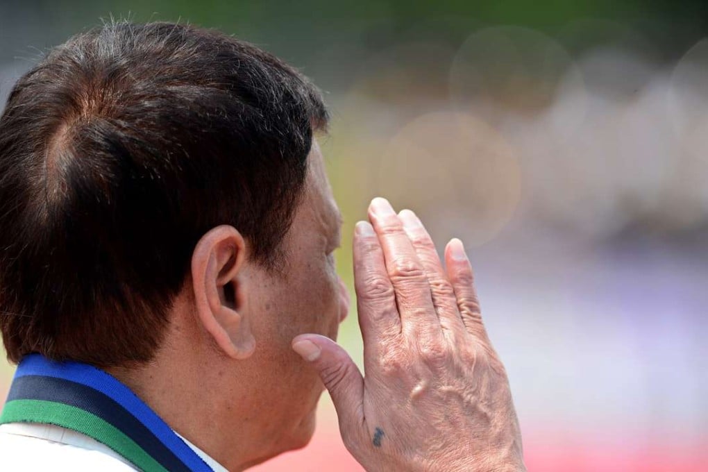 Philippines President Rodrigo Duterte salutes during a military parade. He sports a small tattoo of a soldiers’ group that once staged coups to reinstate dictator Ferdinand Marcos. Photo: AFP