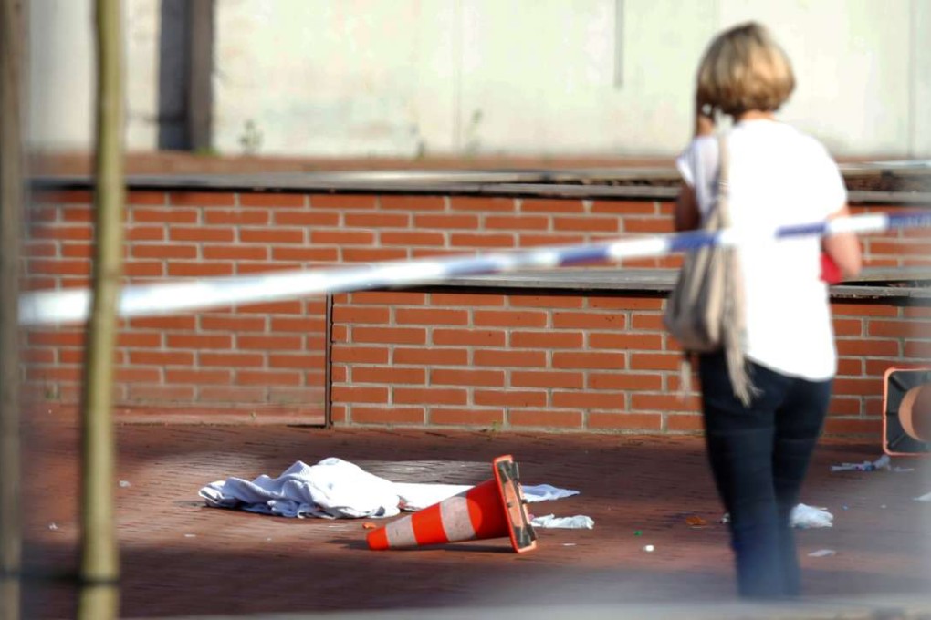 A woman stands at the site where a machete-wielding man injured two female police officers before being shot outside the main police station in Charleroi, Belgium. Photo: Reuters