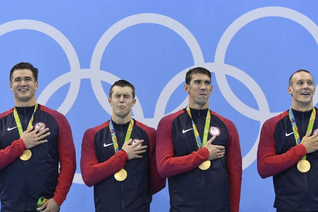Nathan Adrian (left), Ryan Held, Michael Phelps and Caeleb Dressel listen to the US national anthem as they stand on the podium of the Men's 4x100m freestyle relay final. Photo: AFP