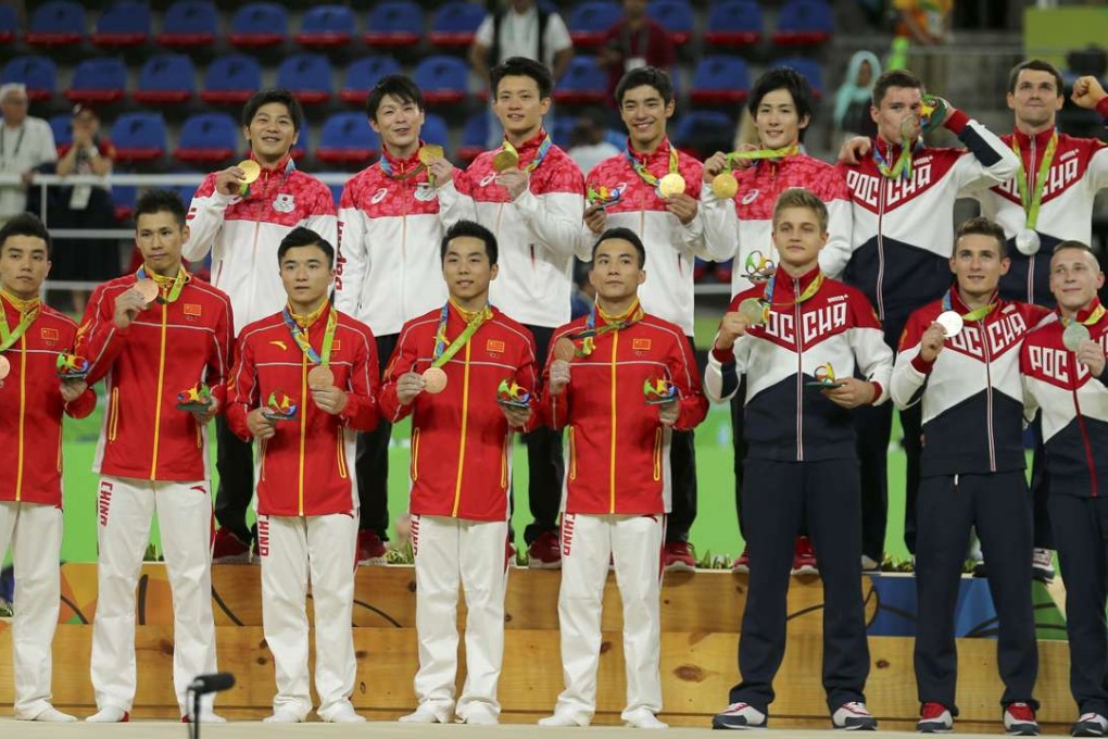 The gymnastic teams of Japan, Russia and China pose with their medals. Photo: Reuters