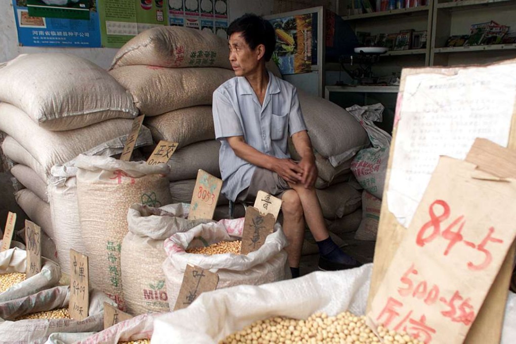 A shopowner waits with sacks of corn and soya beans at the Baoding Seed Market in Hebei province. Photo: AP