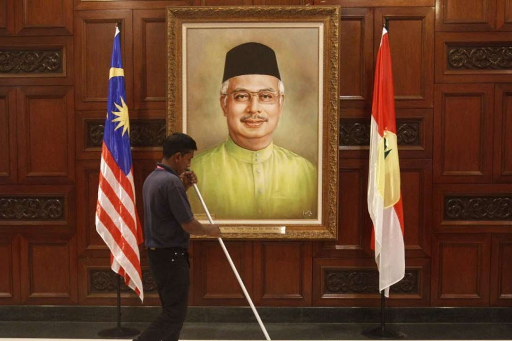 A maintenance worker works near a portrait of Malaysian Prime Minister Najib Razak during the 69th United Malays National Organisation’s (Umno) general assembly in Kuala Lumpur, Malaysia, in 2015. Photo: AFP