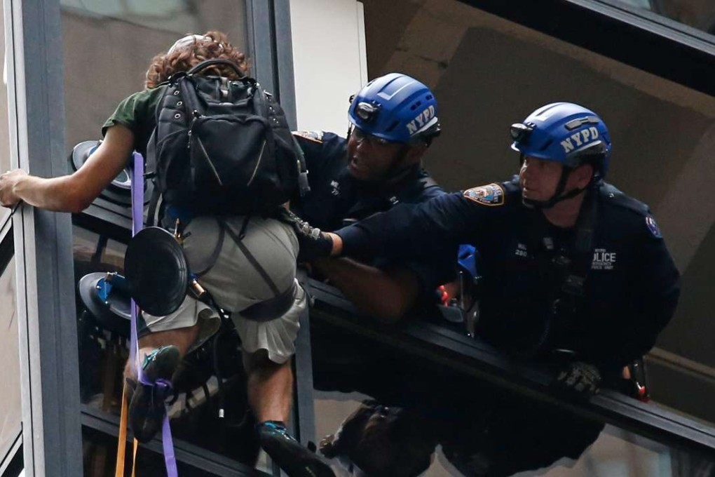 New York City Police grab a man who was climbing the Trump Tower and pull him to safety inside the building through a removed window on the 21st floor in New York on Wednesday. Photo: EPA