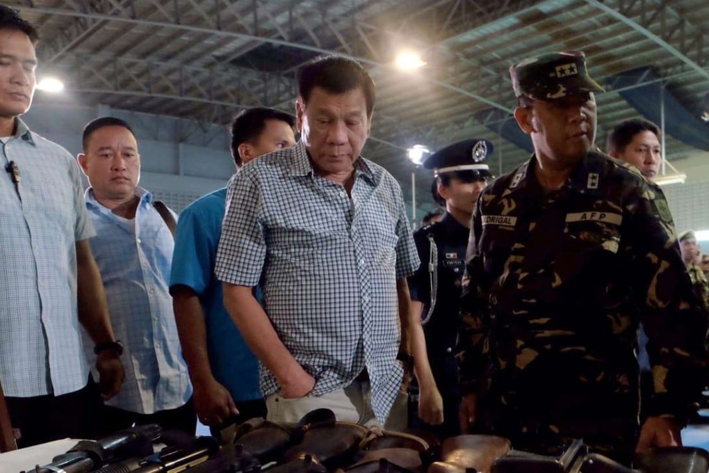 Filipino President Rodrigo Duterte (C) inspect confiscated firearms inside a military camp in Cagayan de Oro City, southern Philippines. More than 800 suspects have been killed and nearly 600,000 people have surrendered to authorities since the president launched his anti-drug campaign more than a month ago. Photo: EPA