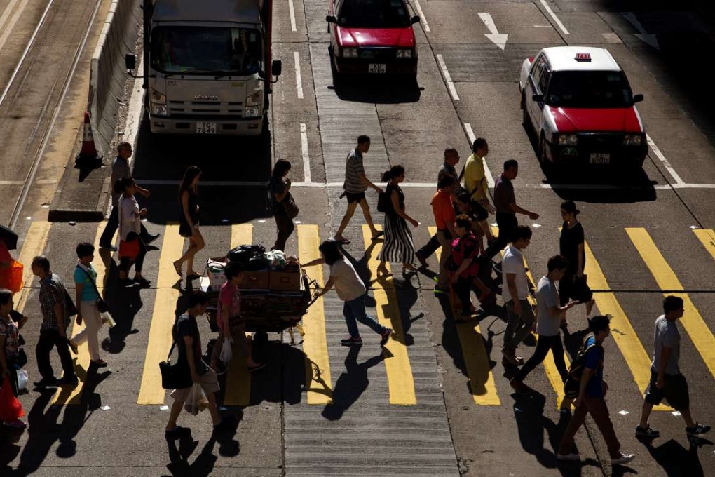 Pedestrians cross a road in North Point. Smart people are key to a smart city. We need people to run a hi-tech city and drive future growth. Photo: Bloomberg