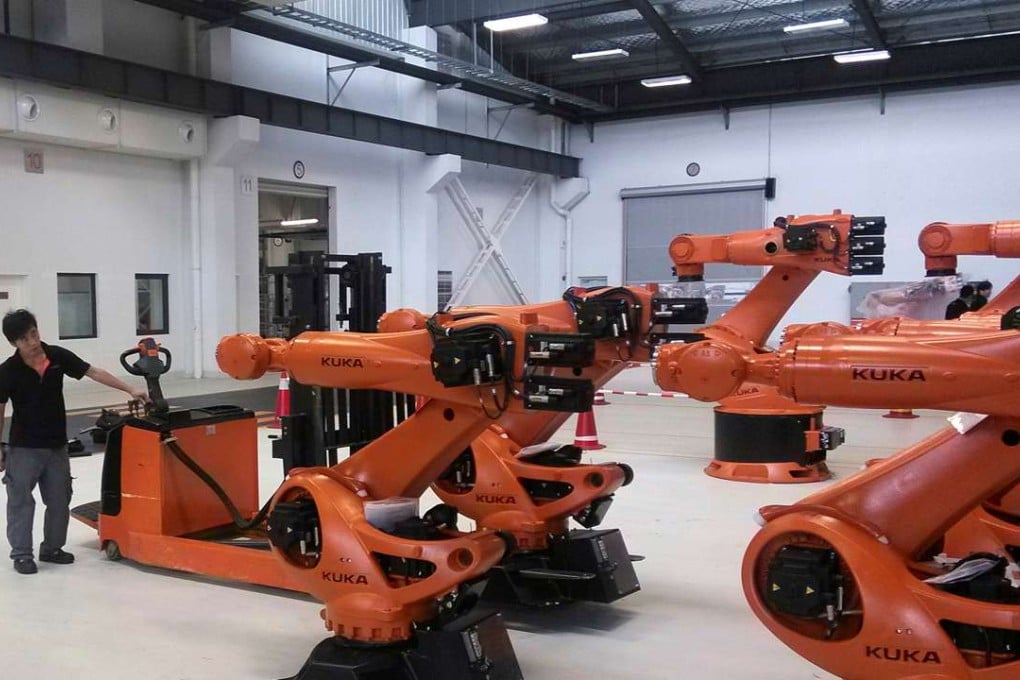 A staff member stands next to robots at a plant of Kuka Robotics in Shanghai, China. Midea on Monday announced it was buying more than 94 per cent of Kuka. Photo: Reuters