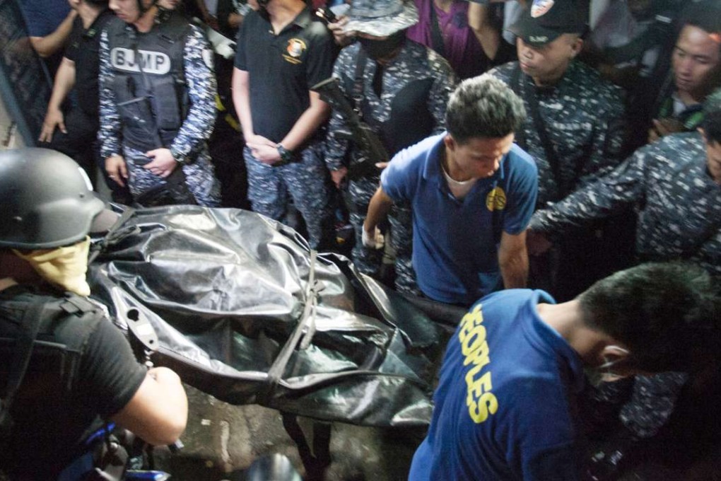 Armed guards from the Paranaque City jail stand beside funeral parlour workers as they carry out the body of a dead prisoner from the jail in Paranaque, suburban Manila early on August 12, 2016. Photo: AFP
