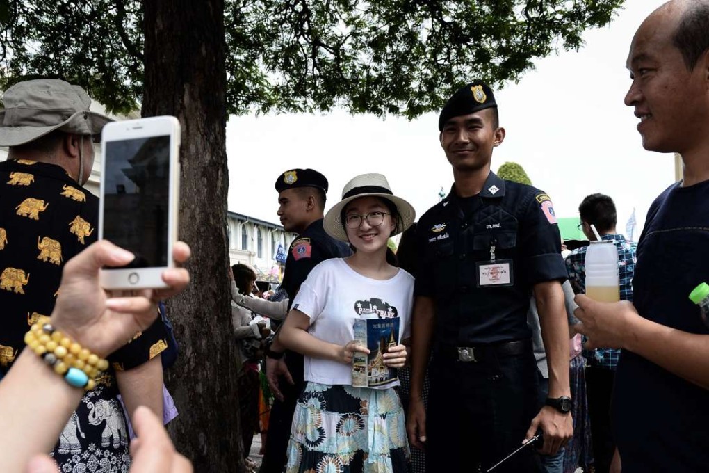 A tourist has her photo taken with a Thai policeman at the Grand Palace in Bangkok. Thai police said they ‘know who was behind’ a recent wave of bombings that rocked tourist destinations across the south. Photo: AFP