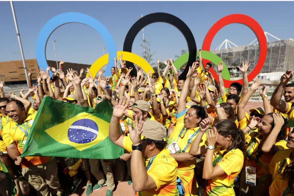 Volunteers cheer around a set of Olympic rings in Rio de Janeiro, Brazil, prior to the start of the 2016 games. Photo: AP