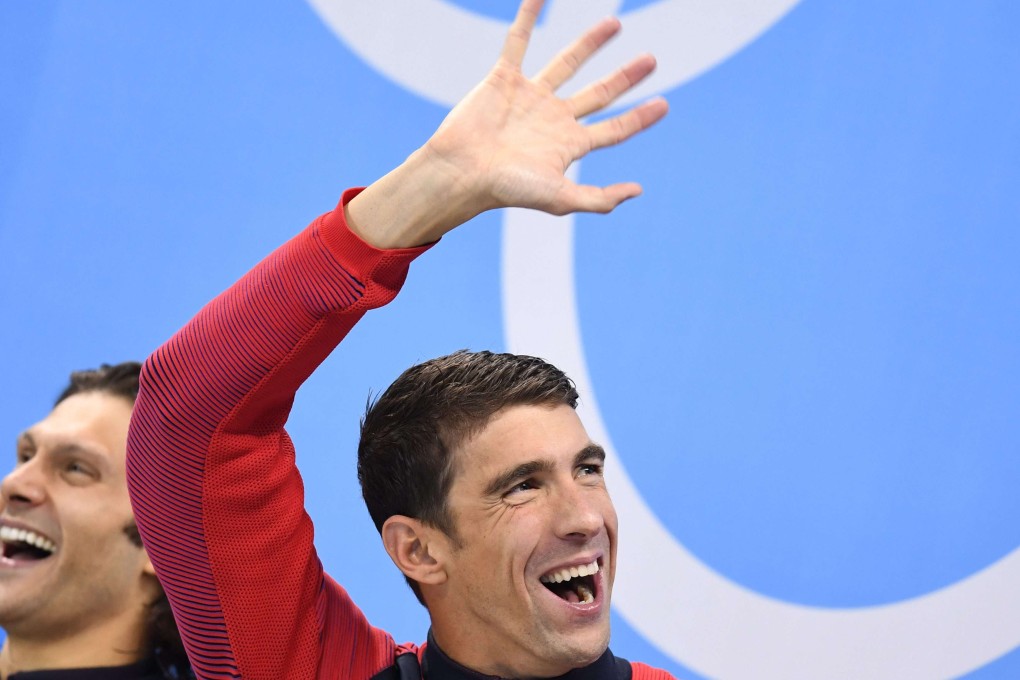 Michael Phelps waves to the crowd during the medal ceremony for the men's 100m butterfly final. Photo: EPA